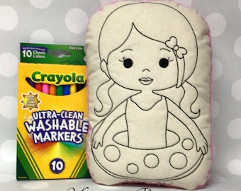 May include: A plush pillow featuring a girl in a swimsuit and inner tube, outlined in black, ready to be colored. A box of 10 Crayola washable markers is next to the pillow. The text "Monogram Perfect" is at the bottom.