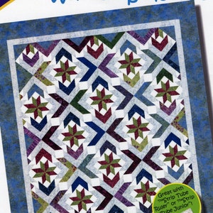 May include: A quilt pattern named "Winter Solstice" by Cozy Quilt Designs. The design showcases a geometric pattern with star and arrow shapes in blue, green, purple, and burgundy. The pattern is for 6.35 cm strips and includes sizes for lap, throw, twin, queen, and king quilts.