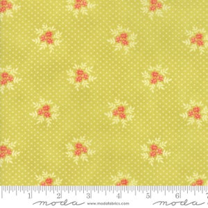 May include: A green fabric with a white polka dot pattern and a repeating floral design in shades of red and white. The fabric has a "moda" label with the website address "www.modafabrics.com".