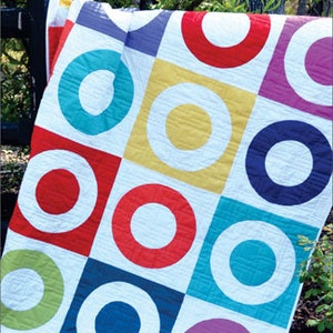 May include: A colorful quilt with a geometric pattern of circles and squares. The quilt is made up of various colors, including red, blue, green, yellow, and purple. The quilt is called "Insider Trading" and is made by "Swirly Girls".