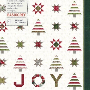 May include: A quilt pattern featuring a Christmas theme with red, green, and white stars and trees. The pattern is called "Spread Joy" and is designed by Natalie Crabtree for BasicGrey.