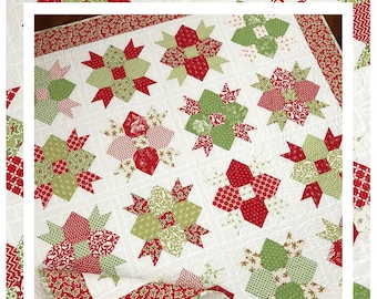 May include: A quilt pattern featuring a white background with red and green star-shaped blocks. The quilt is titled "Ribbons and Bows" and is available from The Pattern Basket, Margot Languedoc Designs. www.thepatternbasket.com