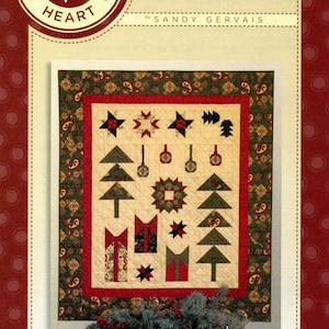 May include: Christmas Sampler Layer Cake pattern quilt block design by Sandy Gervais. The quilt block features a red, green, and white color scheme with a variety of Christmas-themed motifs, including trees, stars, and ornaments.