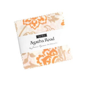 May include: A stack of fabric squares with an orange and beige floral pattern. The fabric is wrapped with a white band that reads "Agatha Road" by Joanna Figueroa, Fig Tree & Co. The fabric is from Moda Fabrics.