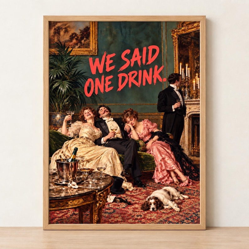 We Said One Drink Victorian party scene print in a light wood frame, leaning against a white wall on a wooden floor, professionally printed
