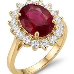 Puede incluir: Un anillo de oro con una gran piedra preciosa de color rojo intenso y corte ovalado en el centro, rodeada por un halo de pequeñas piedras blancas redondas. La banda es de metal amarillo y tiene el número 925 grabado en la parte interior.