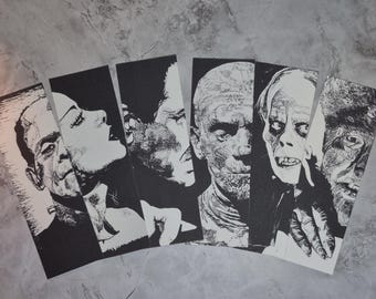 Könnte beinhalten: Eine Sammlung von sechs Schwarz-Weiß-Kunstdrucken mit klassischen Horrorfilmfiguren. Die Drucke zeigen Porträts von Frankensteins Monster, einem Vampir, der Mumie, dem Phantom der Oper und dem Wolfsmenschen.