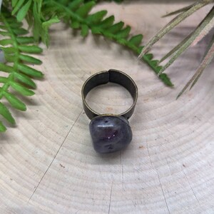 May include: A ring with a purple amethyst stone set in a bronze band.