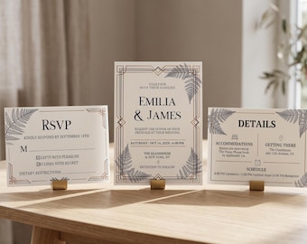 May include: A wedding invitation suite featuring a central invitation, an RSVP card, and a details card. Each white card has black text, gold geometric borders, and black fern leaf illustrations. The text includes names Emilia and James.