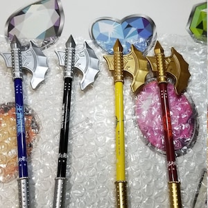 May include: Four silver and gold axe-shaped pens with black, blue, yellow, and red accents. The pens have a silver or gold tip and are decorated with stars and Chinese characters.