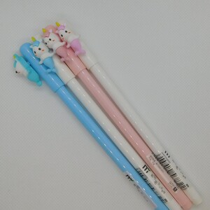 May include: Four unicorn-shaped pens with blue, pink, and white barrels. The pens have a unicorn head with a gold horn and a mermaid tail.