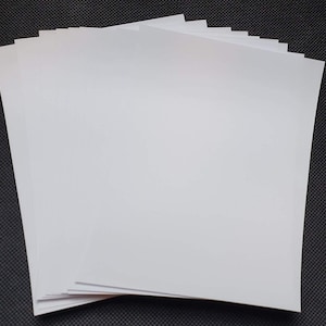 Puede incluir: Una pila de papel de cartulina blanca.