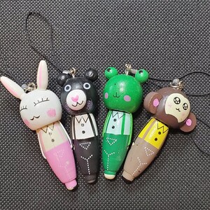 May include: Four wooden figurines with painted faces and clothing. The figurines are a rabbit, a bear, a frog, and a monkey. Each figurine has a loop at the top for hanging.