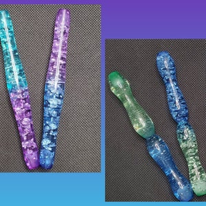May include: Five glass rods with a swirled, marbled effect in various shades of blue, green, and purple. The rods are approximately 15 cm long.