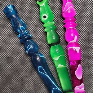 May include: Three decorative handles with swirling patterns in blue, green, and pink. The handles are made of a translucent material and have a glossy finish.
