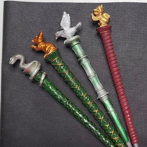 Puede incluir: Cuatro varitas decorativas con detalles en verde y dorado. Cada varita presenta una parte superior de animal diferente: una serpiente, un zorro, un pájaro y un león.