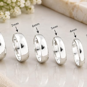 Op de afbeelding: Een set van zes gepolijste zilverkleurige ringen op een rij, elk gelabeld met de breedte: 8mm, 7mm, 6mm, 5mm, 4mm en 3mm. De ringen hebben een glad, afgerond en reflecterend oppervlak, wat een consistent ontwerp toont bij verschillende breedtes.