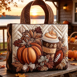 May include: A quilted tote bag featuring an autumn-themed applique design with a large orange pumpkin, a coffee cup with whipped cream, a football, and fall foliage. The bag has a cream-colored chevron quilted background and brown handles.