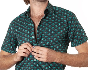 Può includere: Un uomo indossa una camicia a maniche corte con bottoni e un motivo geometrico verde e nero. La camicia ha un colletto e una chiusura con bottoni.