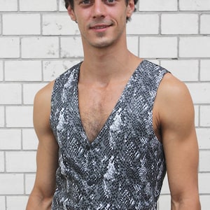 Könnte beinhalten: Eine ärmellose Weste mit Schlangenhautmuster in Grautönen und Weiß. Die Weste hat einen V-Ausschnitt und einen Knopfverschluss.