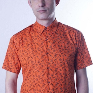 Puede incluir: Una camisa de botones naranja de manga corta con un estampado negro de llaves y tuercas.