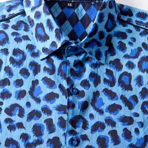 Puede incluir: Una camisa de botones azul y negro con estampado y cuello. El cuello tiene un estampado a cuadros contrastante azul y negro. La camisa tiene el texto "BAISAP" y "XL" en el cuello.