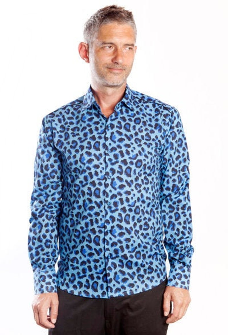 Puede incluir: Una camisa azul de manga larga con botones y estampado de leopardo azul y negro.