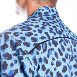Puede incluir: Una camisa de estampado de leopardo azul y negro con ribete negro alrededor del cuello y los hombros.