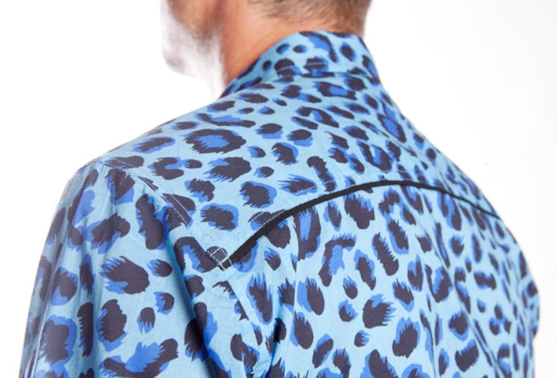 Puede incluir: Una camisa de estampado de leopardo azul y negro con ribete negro alrededor del cuello y los hombros.