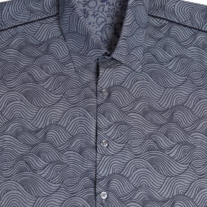Pu&ograve; includere: Una camicia azzurra con bottoni e un motivo a onde. La camicia ha un colletto e una chiusura con bottoni. Il nome del marchio "BAISAP" &egrave; sul colletto.
