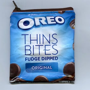 May include: A blue and brown zippered pouch with the text "OREO THINS BITES FUDGE DIPPED ORIGINAL" and images of chocolate sandwich cookies.