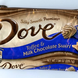 May include: A brown and blue zippered pouch with the Dove logo and the text "Silky Smooth Promises", "Toffee & Milk Chocolate Swirl", "Artificial Flavors", and "Net Wt 7.94 oz (225.1g)".