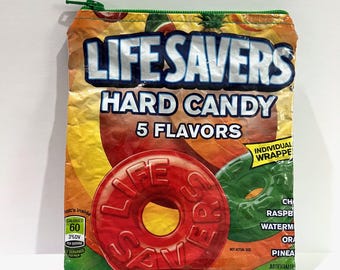 May include: A zippered pouch featuring a design inspired by a Life Savers hard candy package. The pouch displays the words "LIFE SAVERS HARD CANDY 5 FLAVORS" and a large red candy. The pouch is orange, yellow, and green.