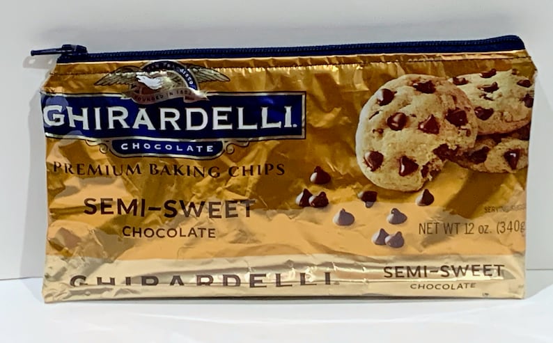 May include: A gold-colored zippered pouch made from a Ghirardelli chocolate chip bag. The pouch features the Ghirardelli logo, the words "Premium Baking Chips," and "Semi-Sweet Chocolate." The image also shows chocolate chip cookies and loose chocolate chips.