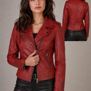 Può includere: Una giacca da moto in pelle rossa con revers dentellati, cerniere in metallo color argento sul davanti e sui polsini, e spalline. Il retro della giacca presenta un grande disegno di un teschio in rilievo tra le scapole.