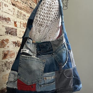 Peut inclure: Un sac à bandoulière de style hobo fabriqué à partir d'un patchwork de divers jeans en denim bleu, avec de multiples poches, des coutures apparentes et une petite étiquette rectangulaire blanche avec du texte noir. Le sac présente des nuances de bleu.