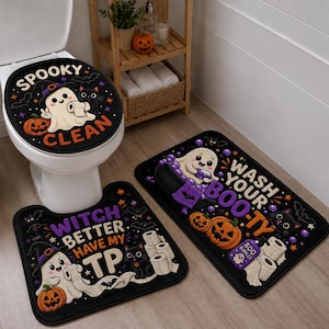 Op de afbeelding: Een driedelige badkamermatset van zwarte stof met Halloween-thema afbeeldingen. De toiletdekselhoes zegt SPOOKY CLEAN, het contourkleed zegt WITCH BETTER HAVE MY TP en het rechthoekige kleed zegt WASH YOUR BOO-TY met spoken, katten en pompoenen.