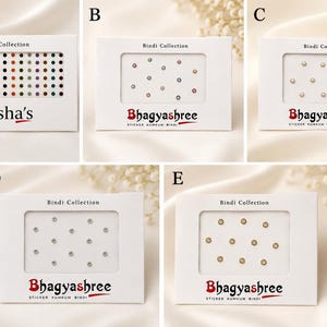May include: Five white rectangular cards labeled Bindi Collection, each containing adhesive bindis. Card A features rows of multicolored bindis labeled Nisha's. Cards B, C, D, and E are labeled Bhagyashree and contain assorted small, circular bindis in various colors, including metallic, pearl-like, and clear stone finishes.