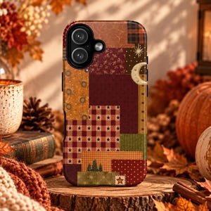 Puede incluir: Una funda de teléfono rectangular con un diseño de patchwork que presenta varios patrones de temática otoñal, incluyendo cuadros, estrellas, lunares y pequeños pinos en tonos burdeos, naranja, amarillo mostaza y verde oliva con una luna.