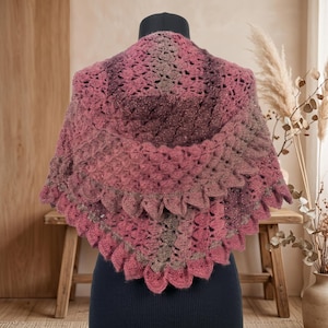 May include: A triangular crochet shawl featuring a gradient of pink and brown yarn with a subtle metallic shimmer. The garment displays a textured, repeating shell stitch pattern throughout, finished with a scalloped, pointed edge.