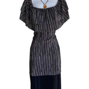 May include: A black dress featuring a white vertical pinstripe pattern on the bodice and sleeves. The garment has a wide, ruffled off-the-shoulder neckline and a solid black skirt section. A brown cord necklace with an amber pendant is included.