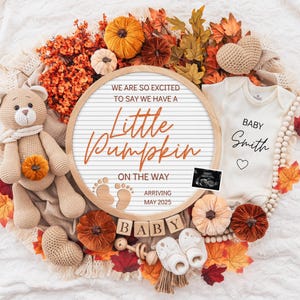 Może przedstawiać: Okrągła tablica z literami z napisem WE ARE SO EXITED TO SAY WE HAVE A Little Pumpkin ON THE WAY, odciskami stóp dziecka i ARRIVING MAY 2025. Zawiera szydełkowego misia, body z napisem BABY Smith, drewniane klocki z napisem BABY oraz jesienne dekoracje.