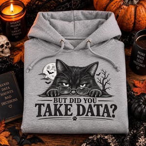 Könnte beinhalten: Ein graumelierter Kapuzenpullover mit einer schwarzen Grafik einer Katze mit Brille, die über eine Kante schaut. Der Text lautet "BUT DID YOU TAKE DATA?" mit einem kleinen Pfotenabdruck. Das Design zeigt einen Vollmond und Fledermäuse.