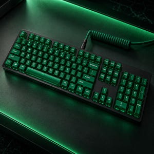 Pode incluir: Um teclado mecânico de tamanho completo com teclas verde-esmeralda translúcidas e letras brancas. O teclado inclui um layout QWERTY padrão, um teclado numérico e um cabo trançado verde em espiral conectado à borda superior do dispositivo.