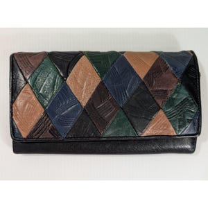 May include: A rectangular wallet featuring a patchwork design of diamond-shaped leather pieces in black, dark green, tan, and navy blue. Each leather segment displays a textured, brushstroke-like pattern across the surface.