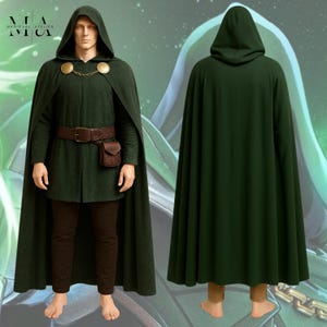 May include: A dark green hooded cloak worn over a matching long-sleeved tunic and dark brown trousers. The cloak features a gold-toned chain clasp with circular accents. A brown leather belt with an attached pouch is worn around the waist.