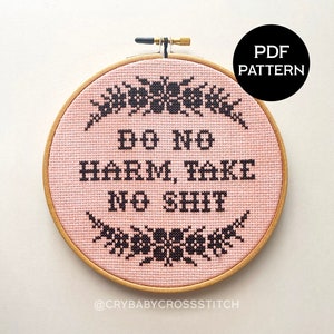 Może przedstawiać: Ręcznie robiony obręcz do haftu krzyżykowego w kolorze różowym i czarnym z napisem "Do No Harm, Take No Shit" i wzorem kwiatowym. Obręcz znajduje się na białym tle. Wzór PDF.