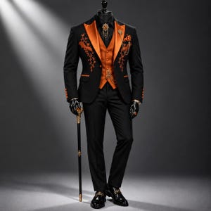 Può includere: Un abito nero con un gilet arancione vivace e revers abbinati. La giacca è decorata con motivi di viti ricamate in arancione e pipistrelli. Il completo include una pochette, una catena dorata come accessorio e un bastone da passeggio nero.