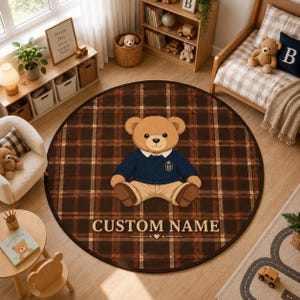 May include: A round area rug featuring a dark brown and black plaid pattern with a central illustration of a teddy bear wearing a navy blue sweater and tan trousers. The text CUSTOM NAME is printed in white below the bear with a small heart icon.