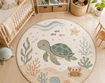 Op de afbeelding: Een rond vloerkleed met een lichtbeige achtergrond en een centrale illustratie van een groene zeeschildpad, omringd door aquarelachtige zeedieren zoals een krab, een zeester, schelpen, koraal, zeewier en kleine vissen in zachte pasteltinten.